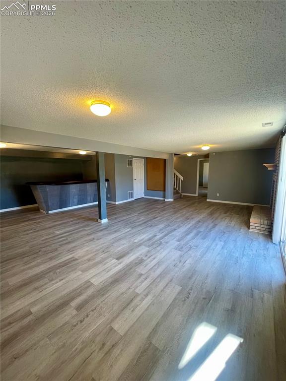 Unfurnished living room with a textured ceiling, light wood-style floors, and a fireplace