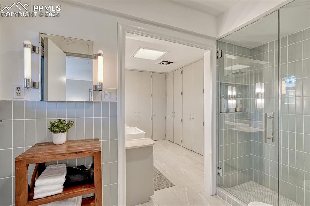 Renovated primary bathroom features Fireclay tile, heated floors and frameless glass shower.