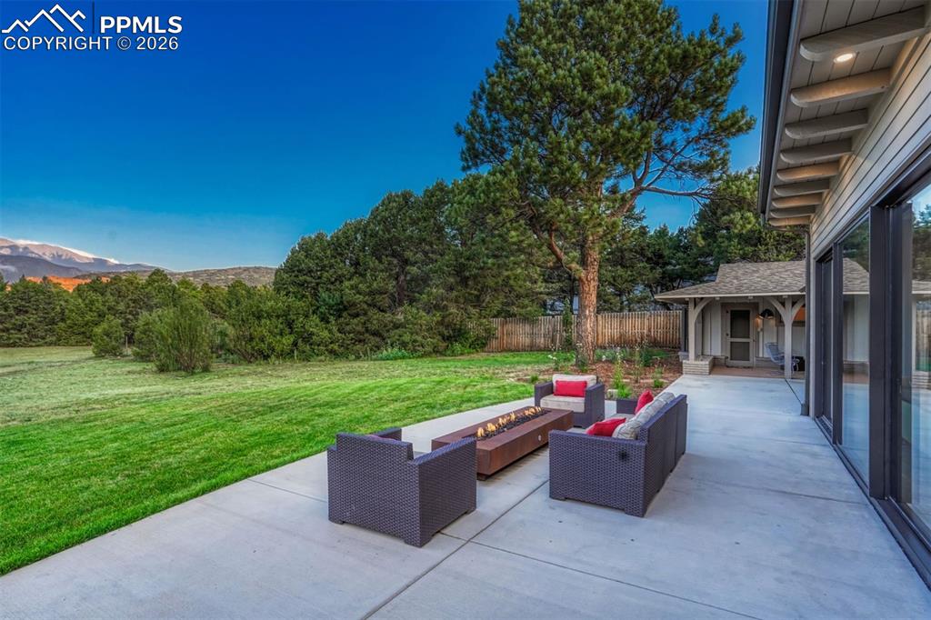 A large patio anchored by a sleek rectangular firepit, opening to the living areas through a stunning NanaWall for effortless indoor-outdoor flow.
