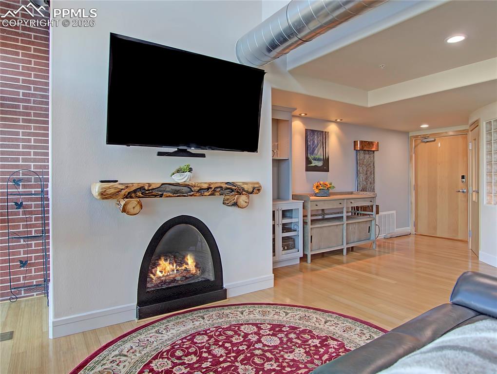 Living room featuring light wood-style flooring, recessed lighting, and a lit fireplace