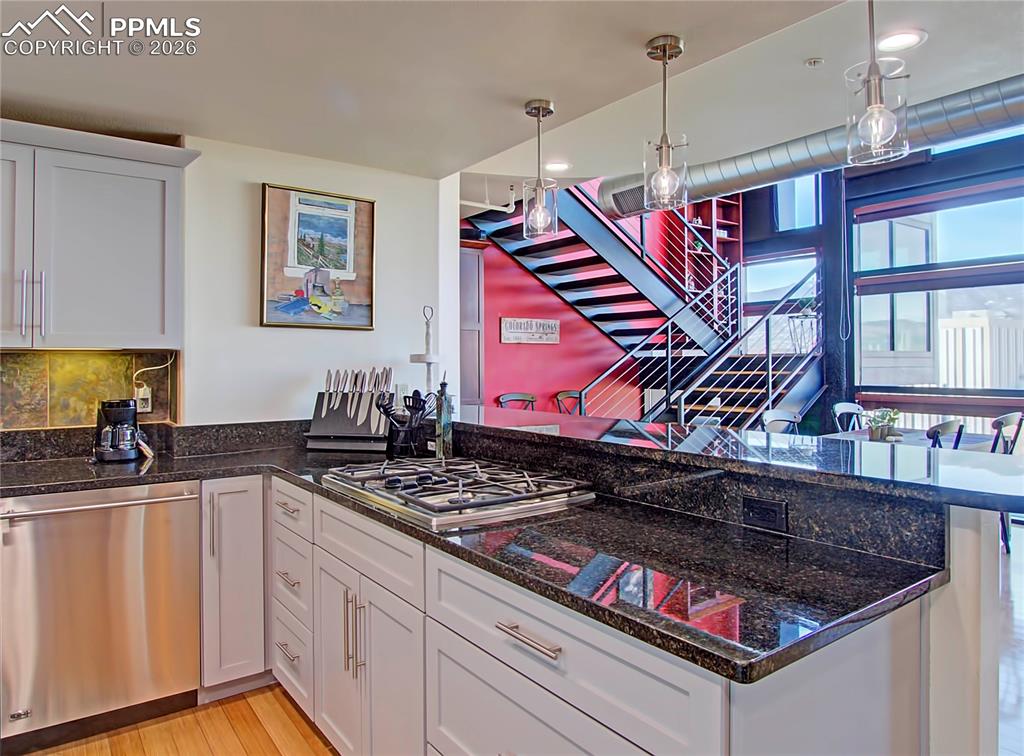 Kitchen with stainless steel appliances, white cabinetry, a peninsula, and pendant lighting