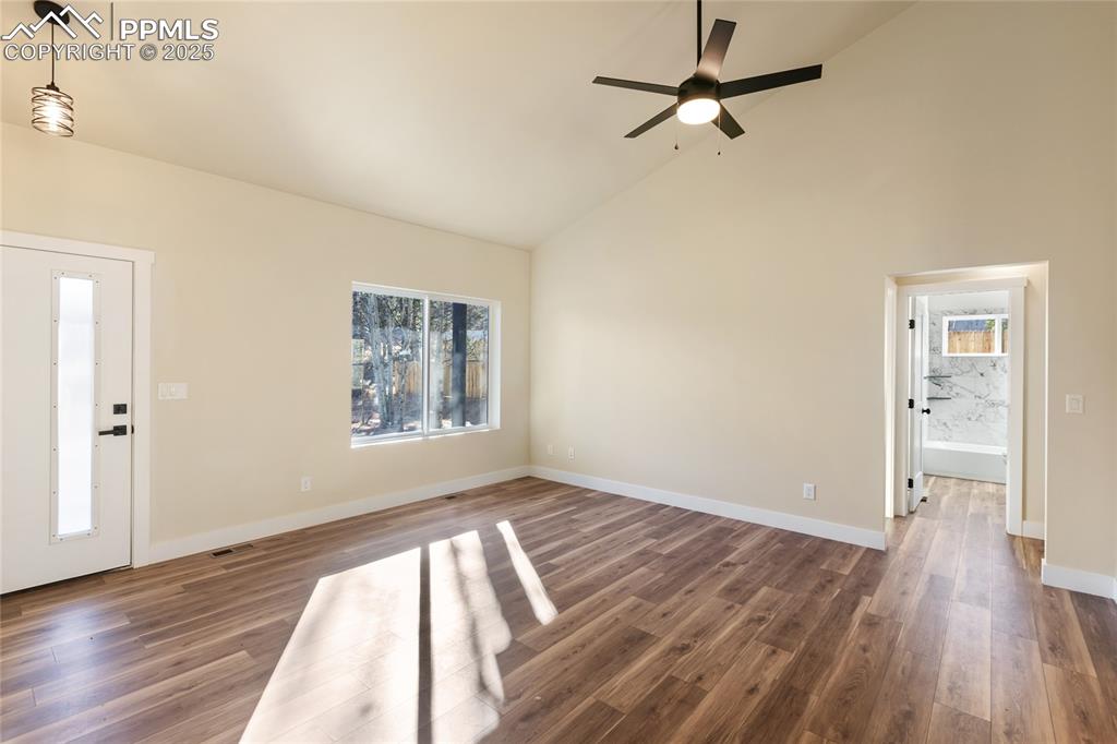 Entrance foyer with high vaulted ceiling, dark wood-type flooring, and ceiling fan