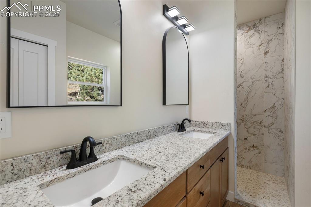 Bathroom featuring double vanity and tiled shower
