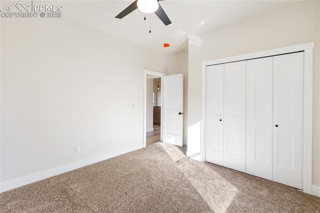Unfurnished bedroom with carpet floors, a closet, and a ceiling fan