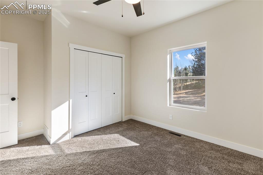 Unfurnished bedroom featuring carpet floors, a closet, and ceiling fan