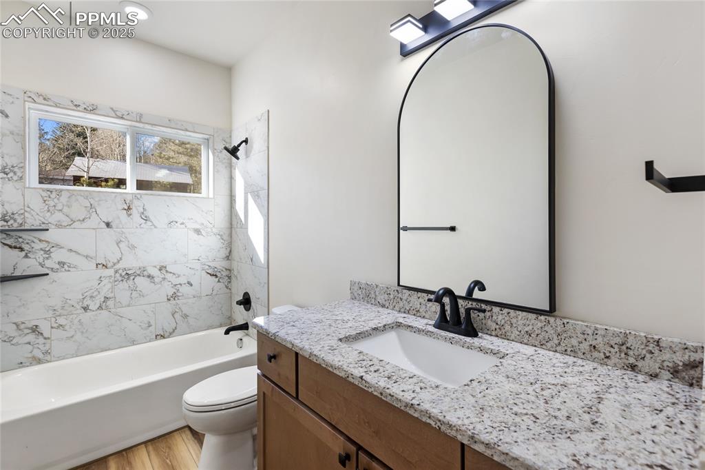 Full bath with shower / bath combination, vanity, and light wood-style flooring