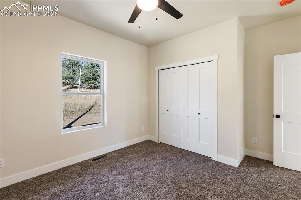 Unfurnished bedroom with dark carpet, a closet, and ceiling fan