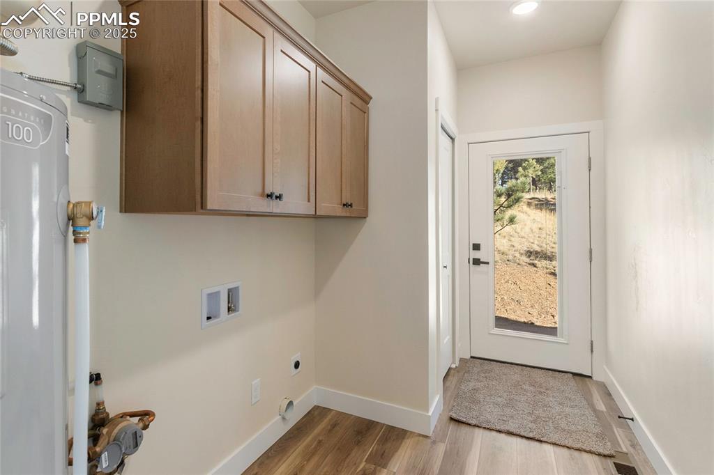 Laundry room with washer hookup, water heater, cabinet space, and light wood-type flooring