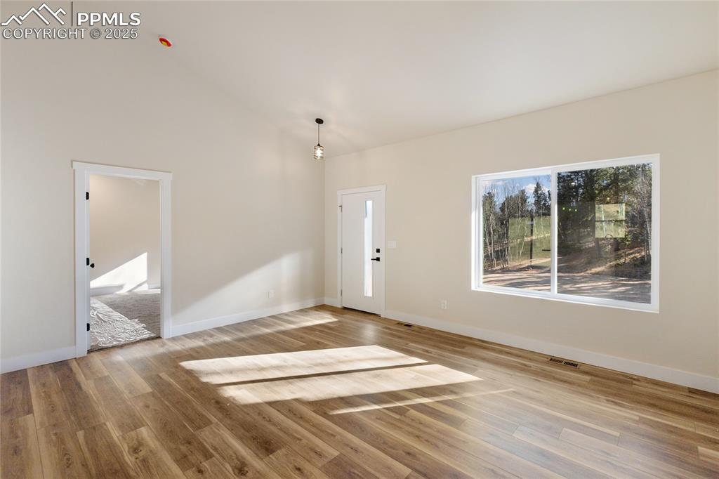 Foyer with light wood-style floors and high vaulted ceiling