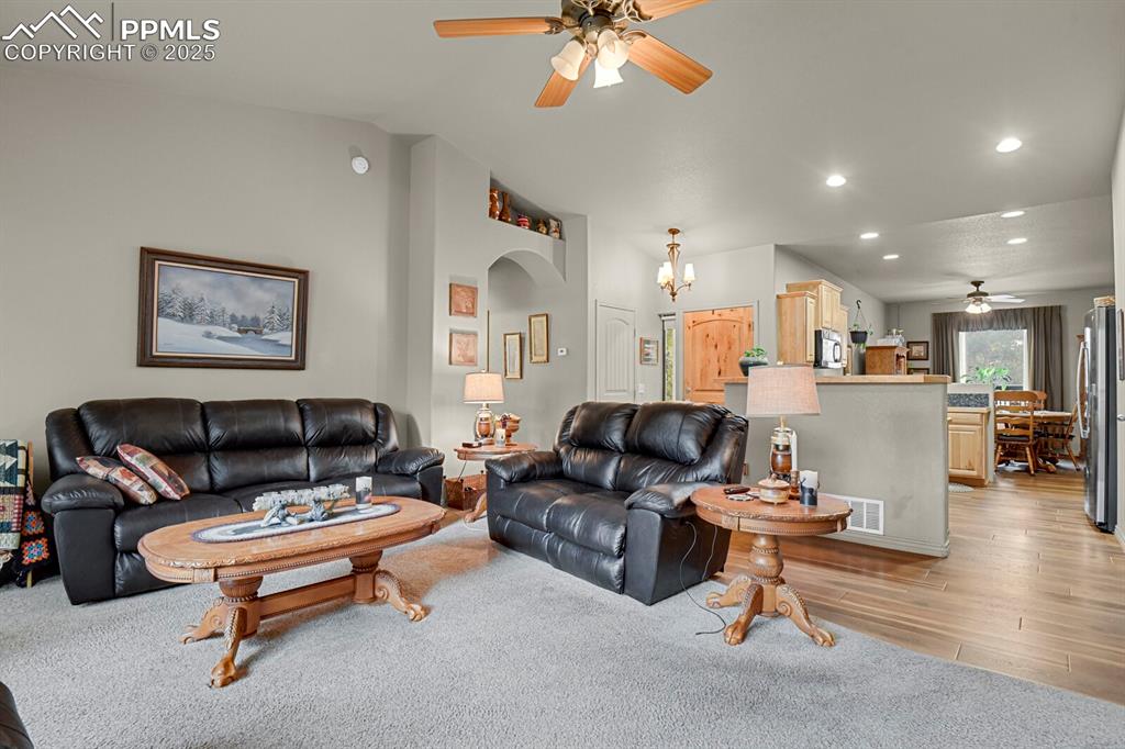 Living room featuring ceiling fan, recessed lighting, light wood finished floors, lofted ceiling, and a chandelier