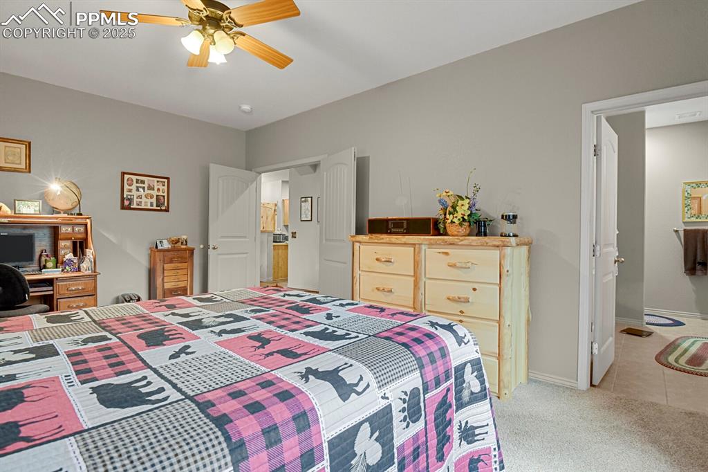 Bedroom featuring light carpet, ceiling fan, and light tile patterned floors