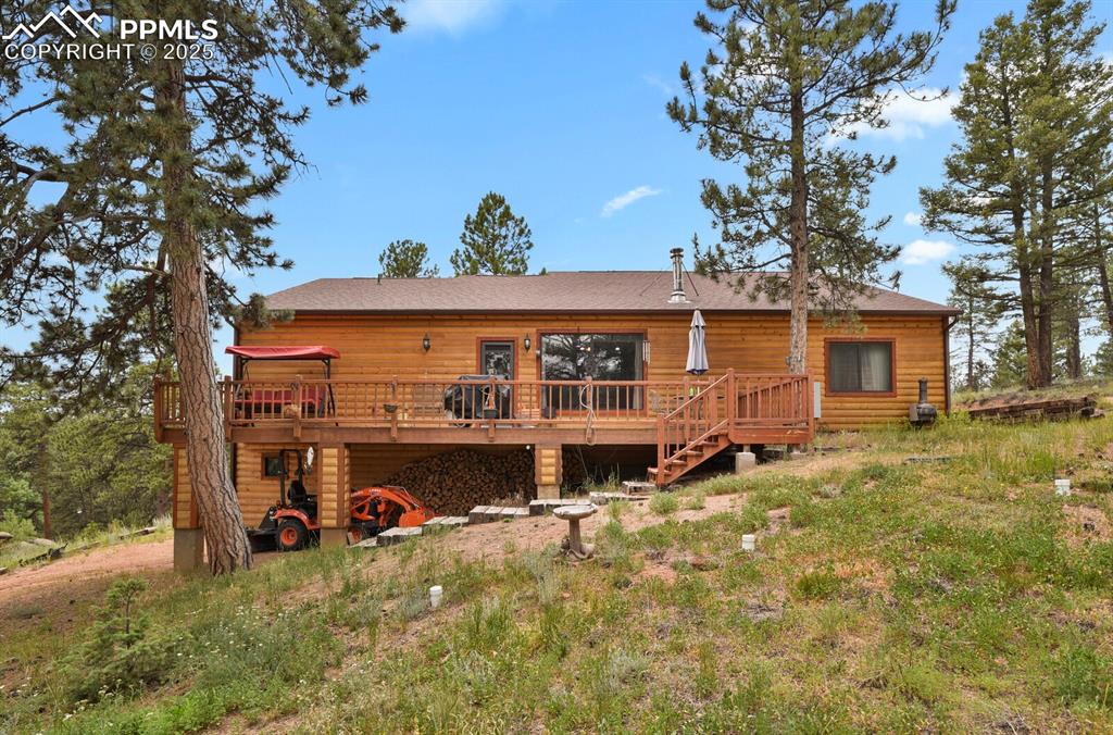 Rear view of property featuring a wooden deck, log veneer siding, stairway, and a shingled roof