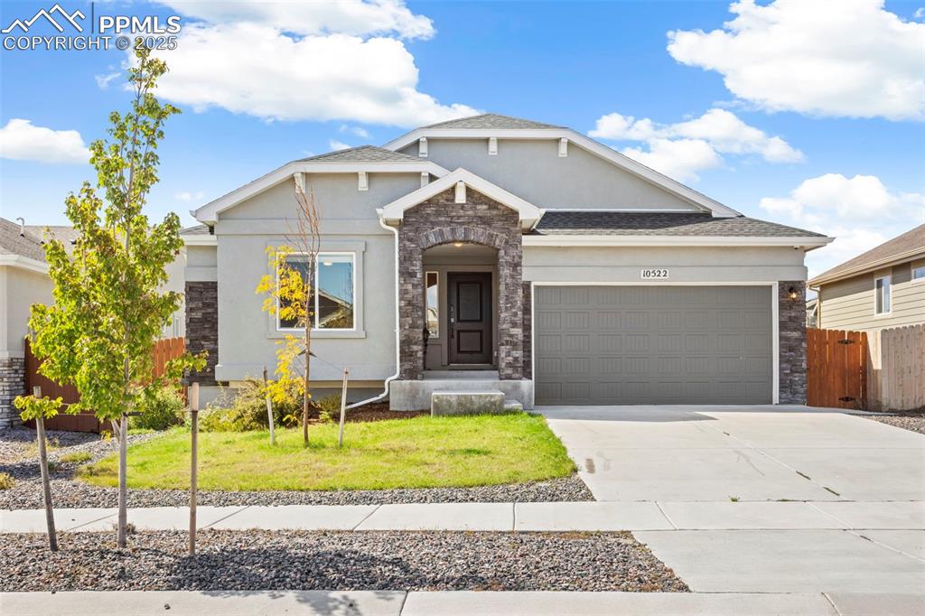 Craftsman house with stone siding, driveway, a garage, and stucco siding