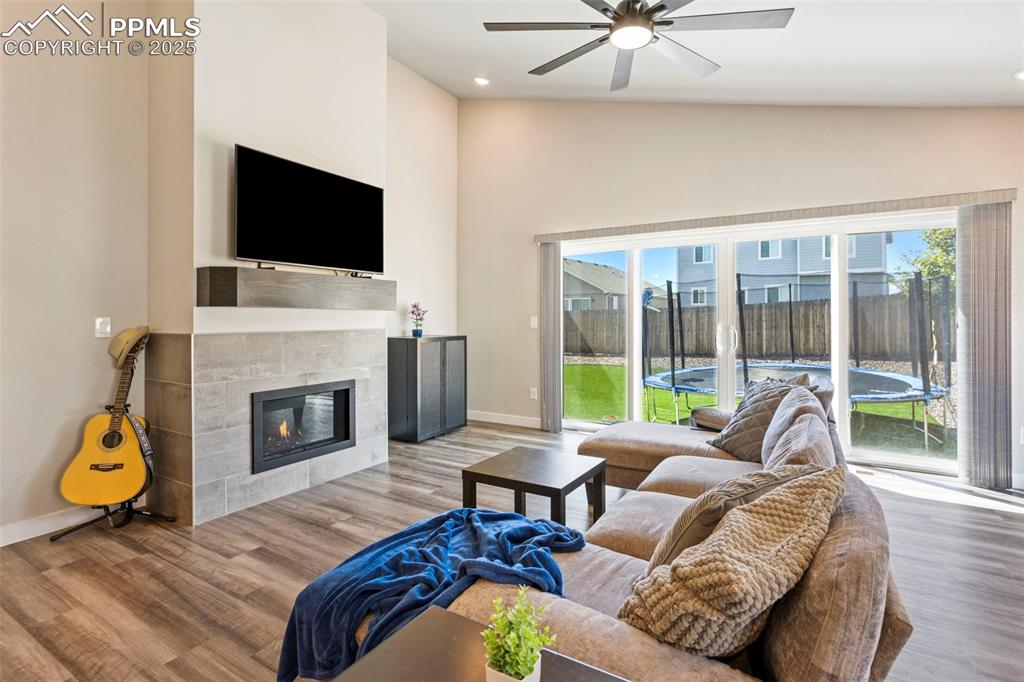 Living area featuring plenty of natural light, a tile fireplace, wood finished floors, high vaulted ceiling, and recessed lighting
