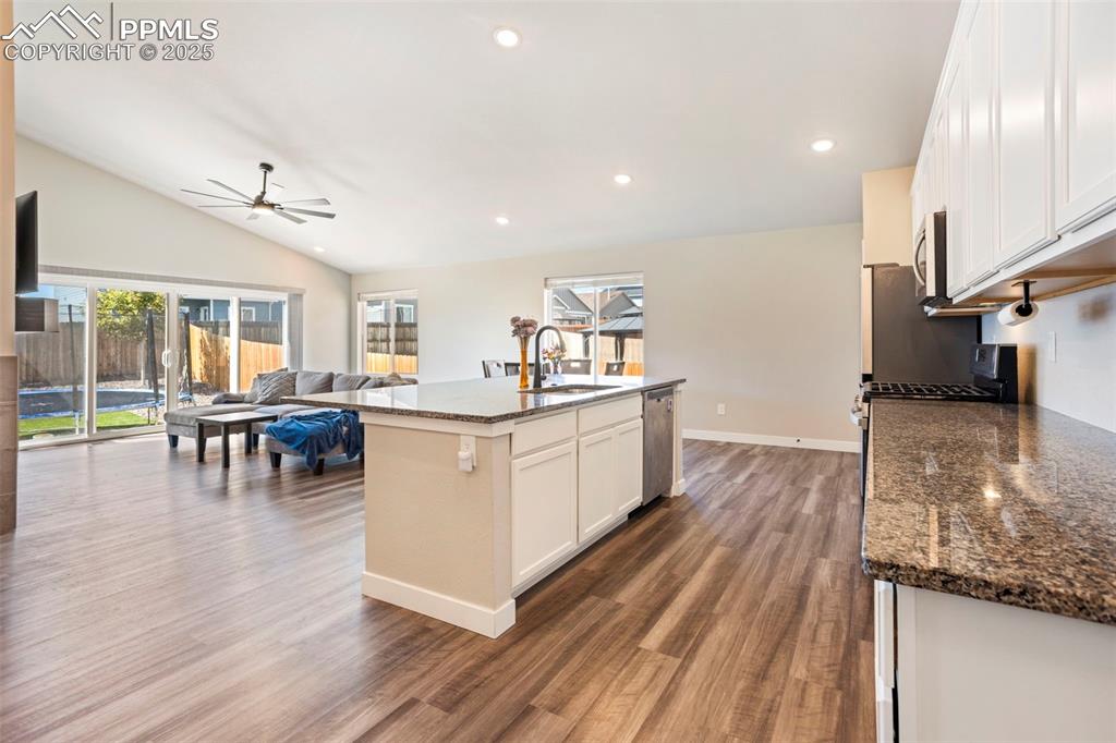 Kitchen featuring white cabinetry, dark stone counters, open floor plan, recessed lighting, and dark wood-type flooring