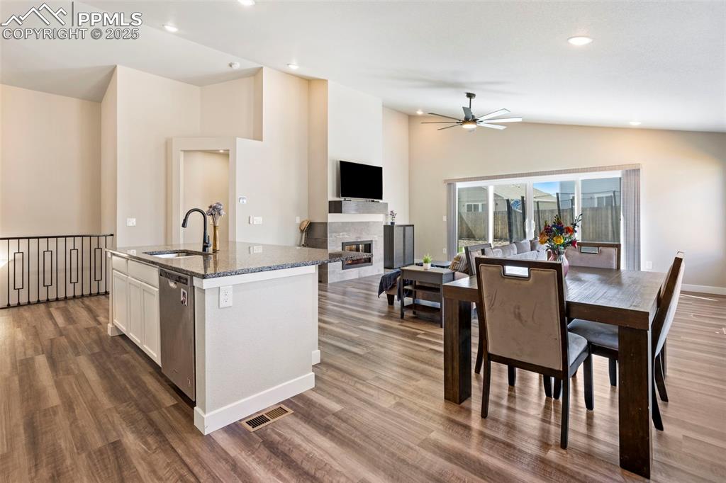 Kitchen featuring dark stone countertops, a kitchen island with sink, open floor plan, white cabinets, and dark wood finished floors