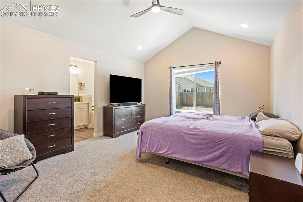 Bedroom featuring light carpet, vaulted ceiling, recessed lighting, ceiling fan, and ensuite bath