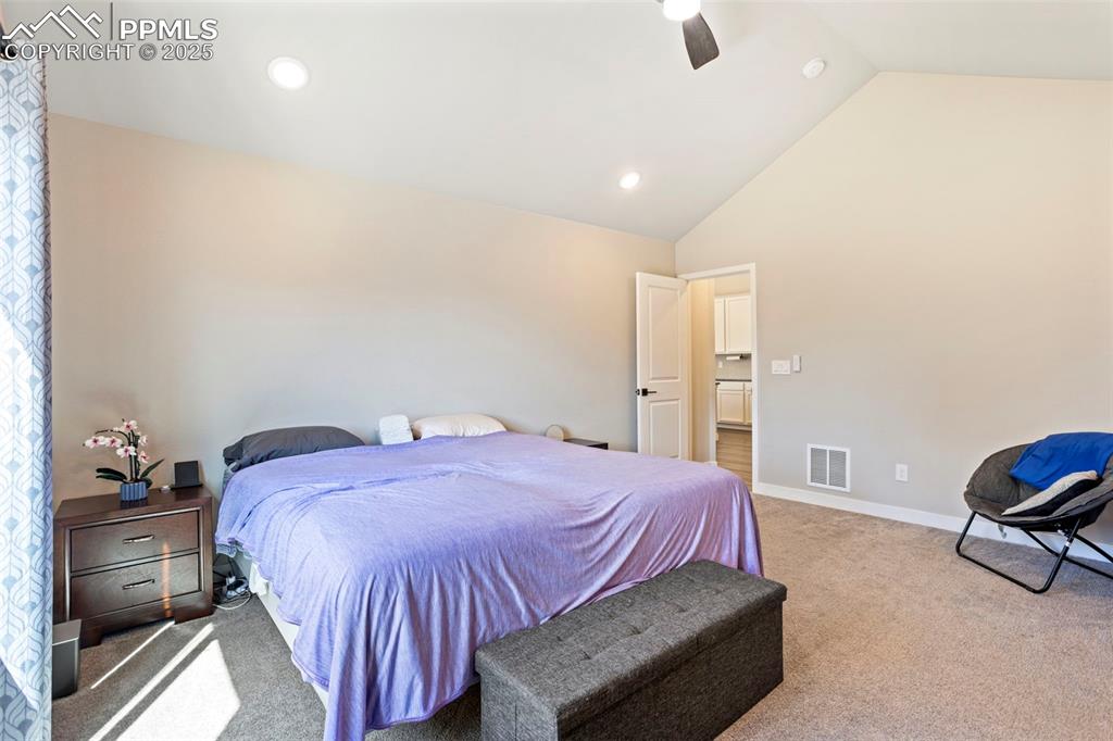 Carpeted bedroom with a ceiling fan, high vaulted ceiling, and recessed lighting