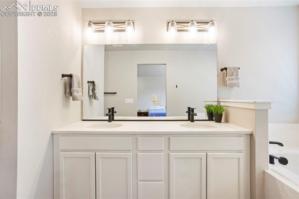 Ensuite bathroom featuring double vanity and a garden tub