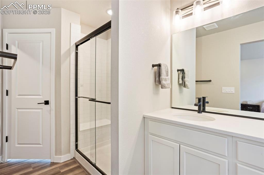 Bathroom with a shower stall, vanity, dark wood-style flooring, and ensuite bath