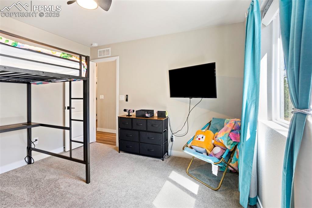 Bedroom with light carpet, multiple windows, and a ceiling fan