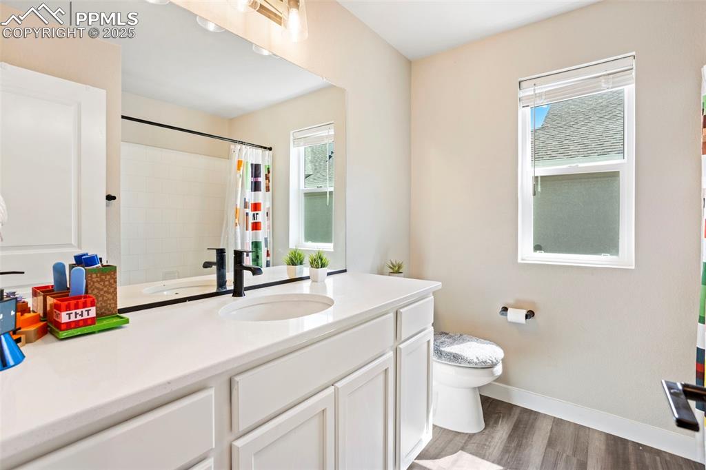 Bathroom with dark wood-style floors, vanity, and healthy amount of natural light