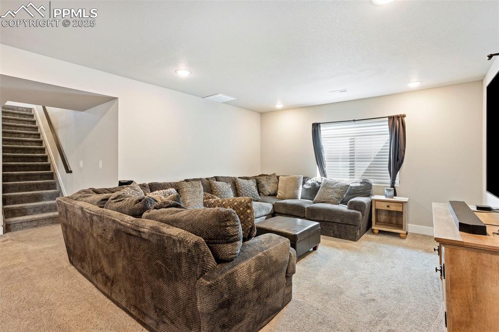 Living area featuring light carpet, stairway, and recessed lighting
