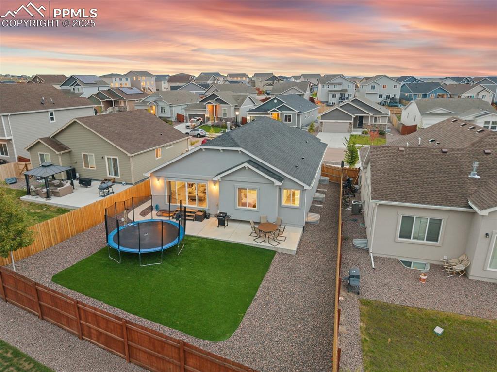 Back of house featuring a patio area, a trampoline, a fenced backyard, and stucco siding