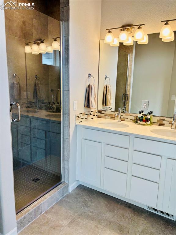 Full bathroom featuring double vanity, a stall shower, and light tile patterned floors