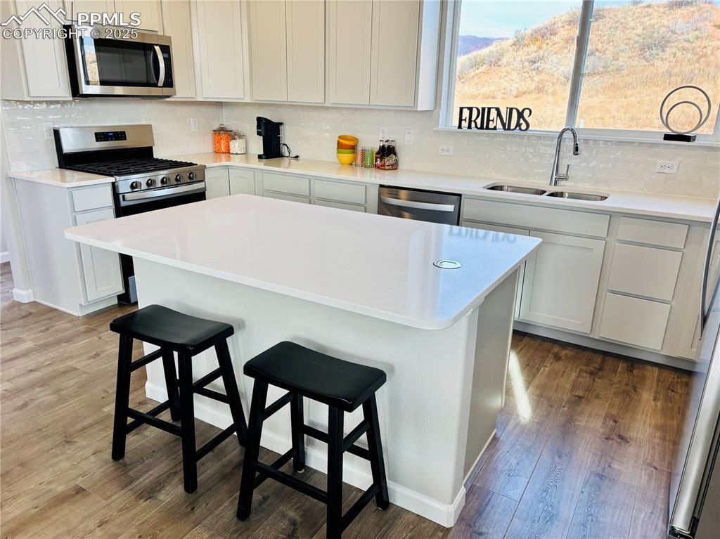 Kitchen featuring a breakfast bar, appliances with stainless steel finishes, a center island, and tasteful backsplash