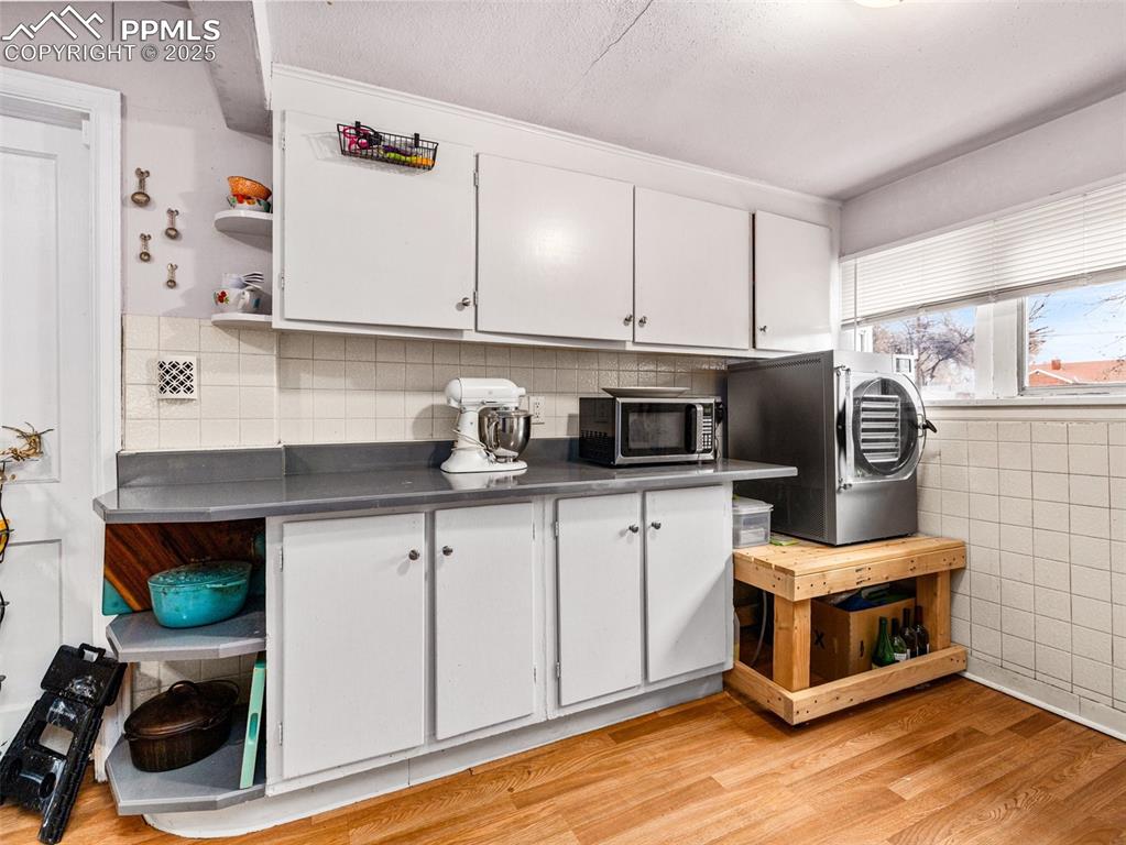 Kitchen featuring open shelves, white cabinetry, washer / dryer, light wood-style flooring, and stainless steel countertops