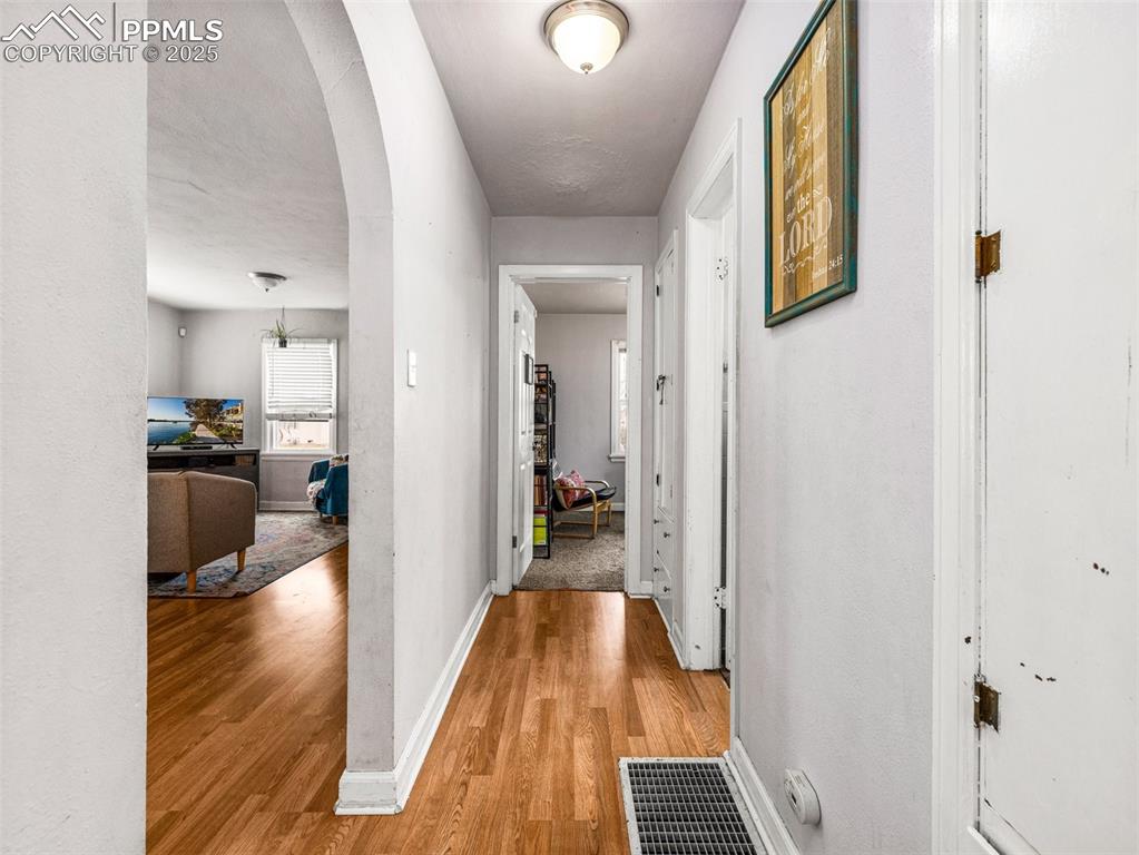 Hall featuring arched walkways and light wood-type flooring
