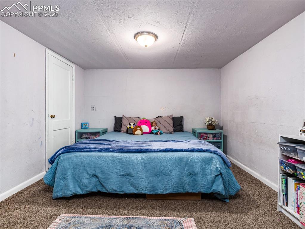 Carpeted bedroom featuring a textured ceiling and baseboards