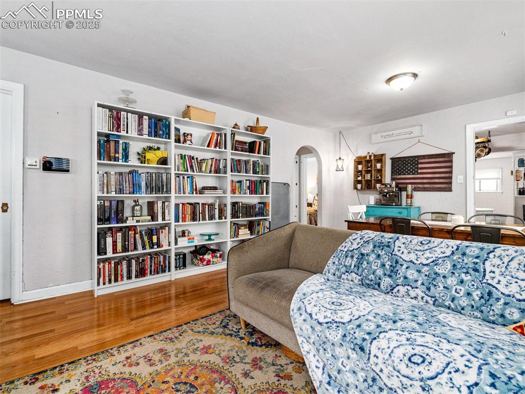 Living room featuring arched walkways and light wood-style flooring