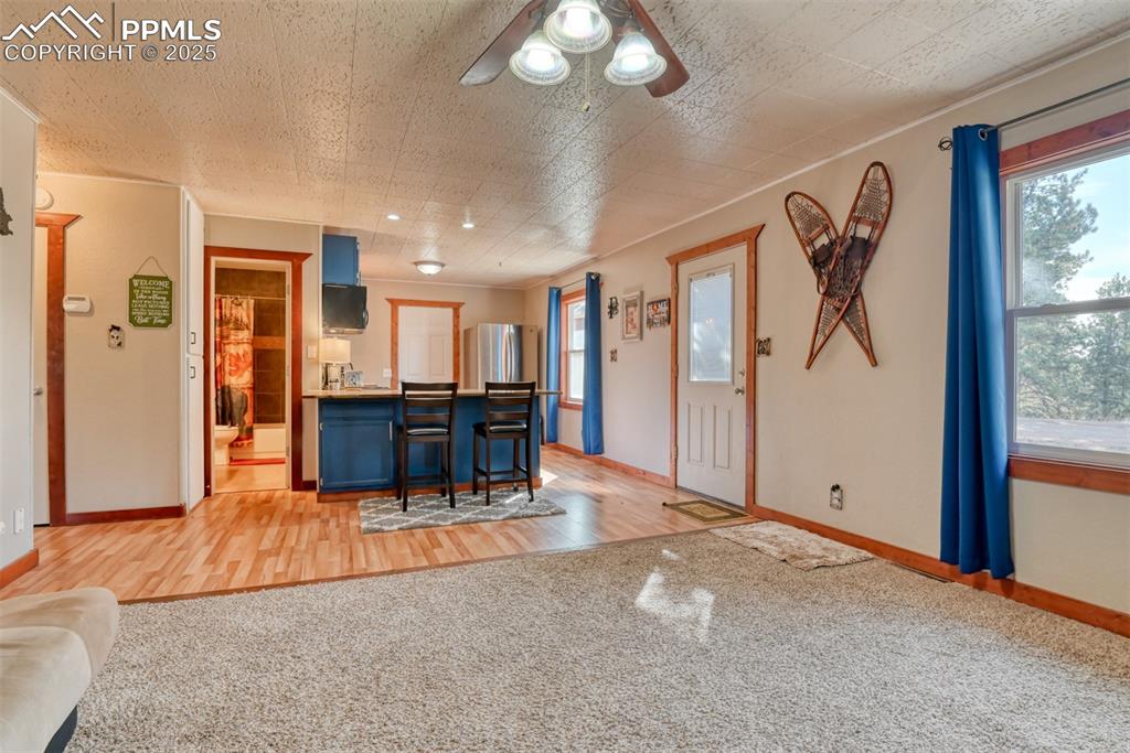 Kitchen featuring blue cabinets, light carpet, a kitchen bar, a peninsula, and ornamental molding