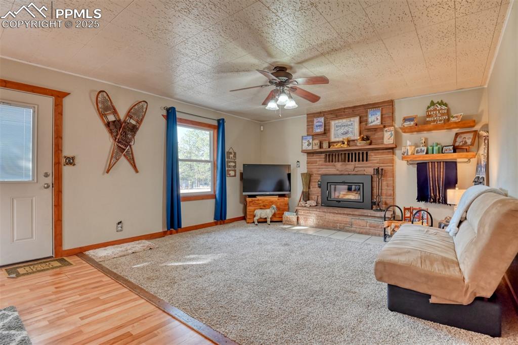 Living area featuring light wood-type flooring, ceiling fan, and a fireplace