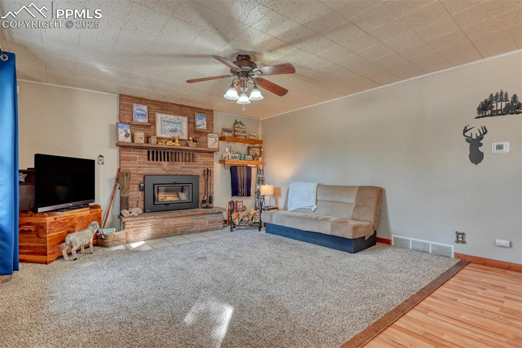 Living area featuring a fireplace, a ceiling fan, and wood finished floors
