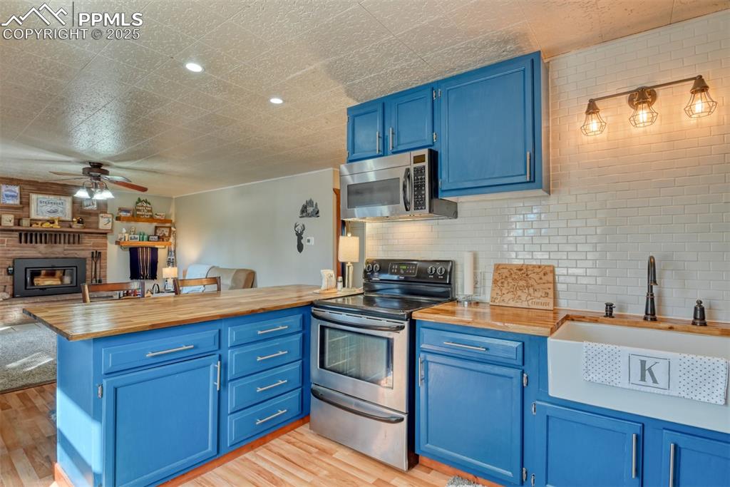 Kitchen featuring blue cabinetry, open floor plan, appliances with stainless steel finishes, a peninsula, and recessed lighting