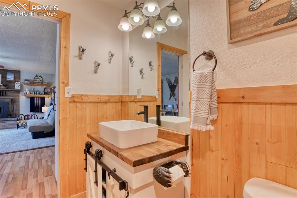 Bathroom featuring wood walls, wood finished floors, vanity, a chandelier, and ensuite bathroom