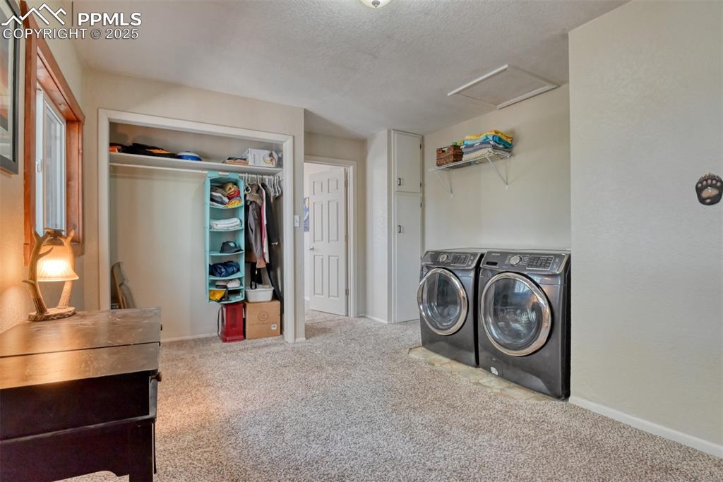 Laundry area featuring light colored carpet, washer and clothes dryer, attic access, and a textured ceiling