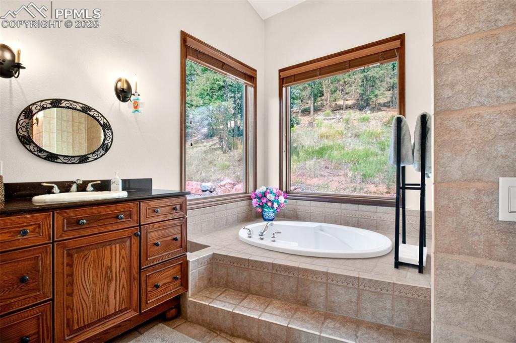 Primary en suite 5 piece bathroom highlighting the soaking tub and private views out of the windows