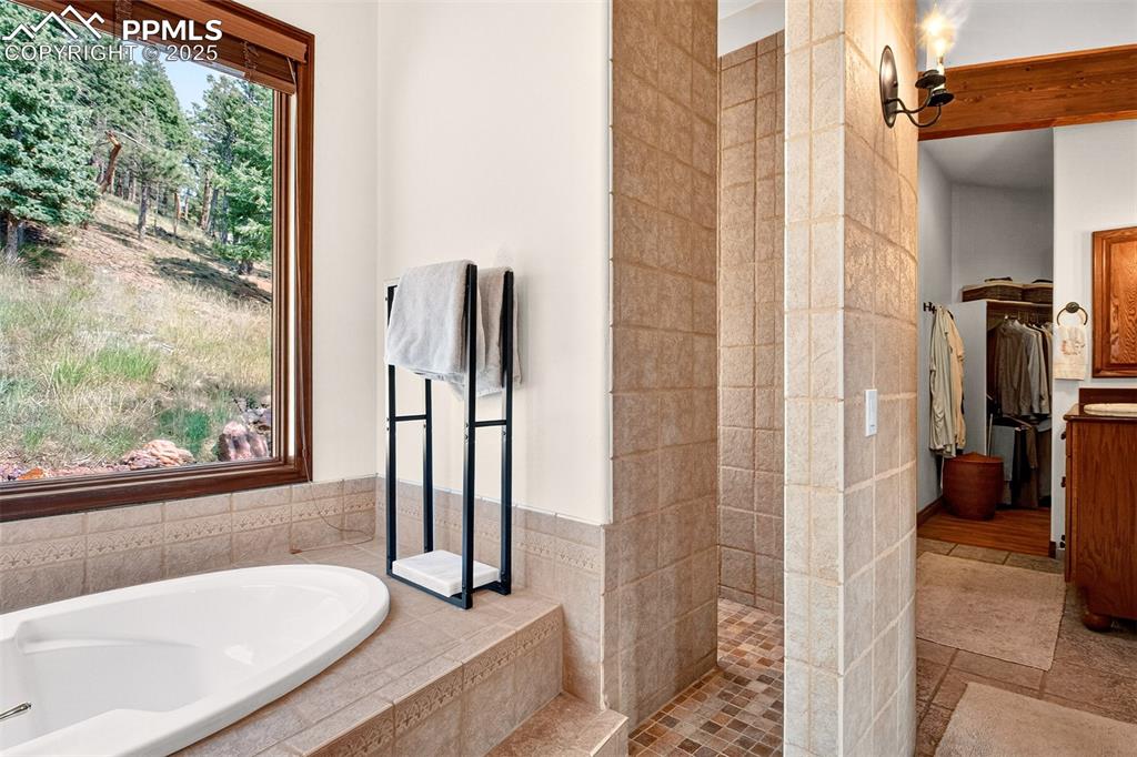 Primary en suite bathroom with soaking tub, custom shower and walk in closet