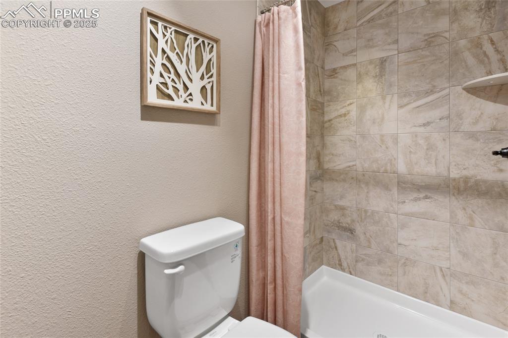 Bathroom featuring a textured wall and a stall shower
