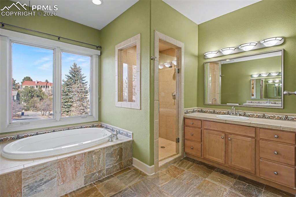 Primary bathroom with natural stone, double vanity, tub, and walk-in shower. 