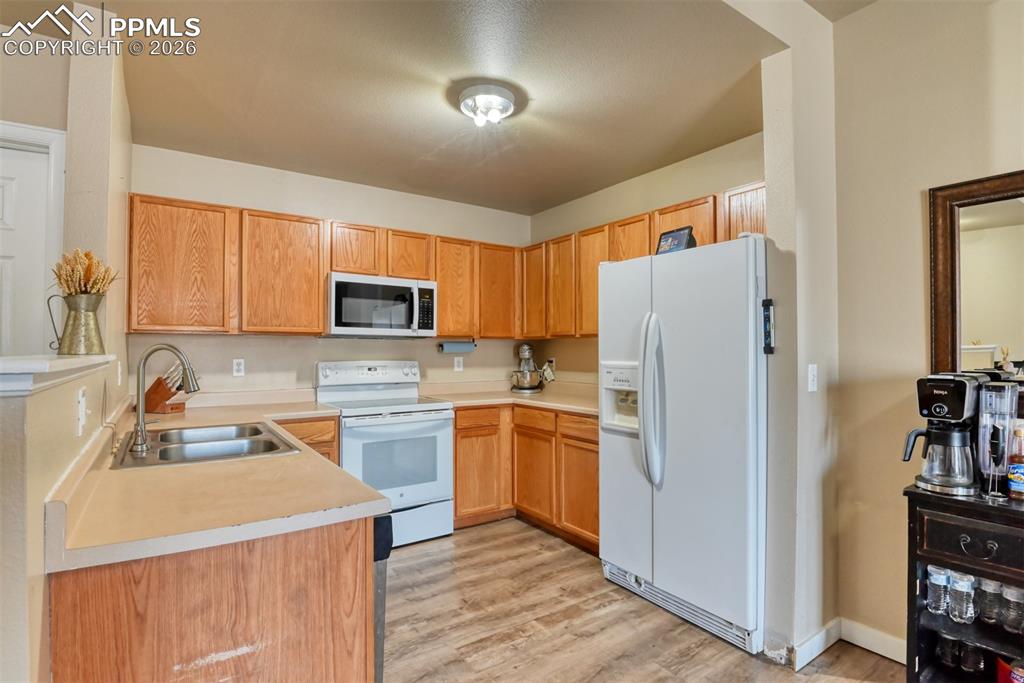 Kitchen featuring white appliances, light countertops, light wood-style floors, and wood finish cabinetry
