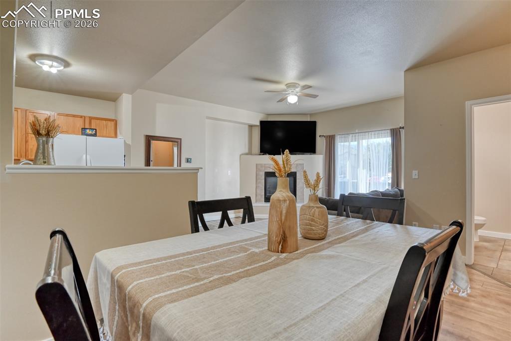 Dining space featuring ceiling fan, a fireplace, and a textured ceiling
