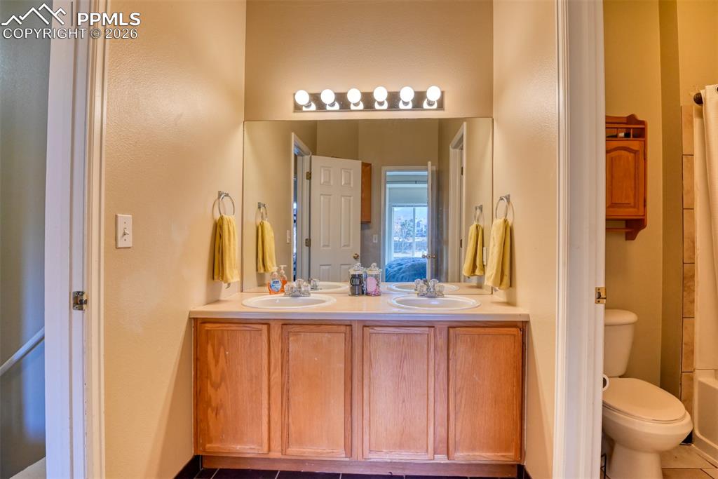 Bathroom featuring double vanity and dark tile patterned floors