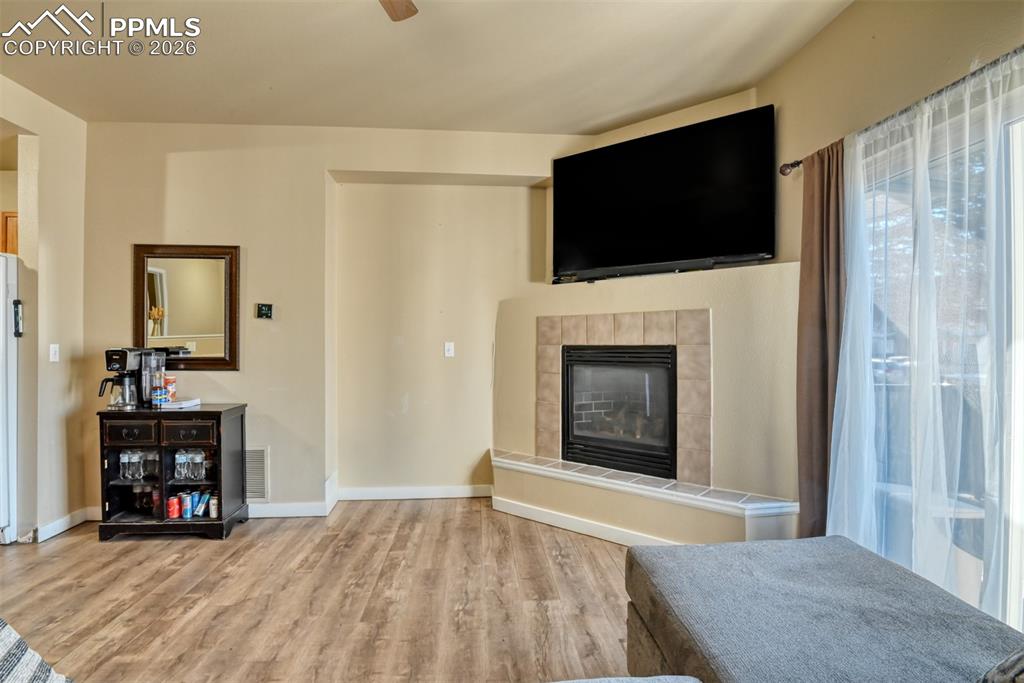 Living area featuring a tile fireplace, ceiling fan, and light wood-type flooring
