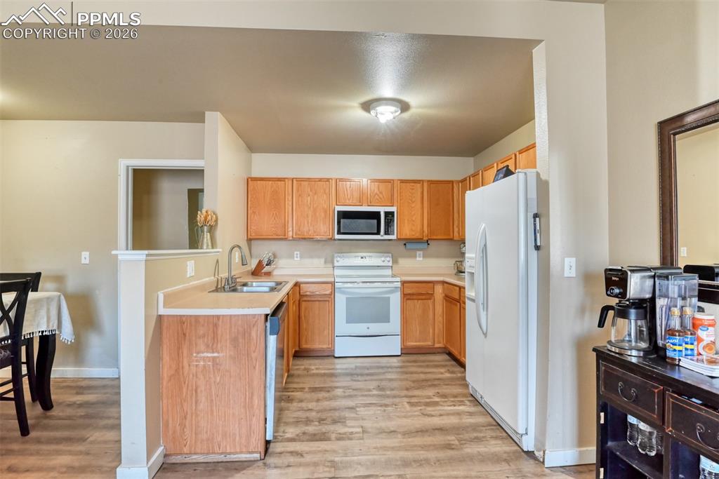 Kitchen featuring light countertops, white appliances, light wood-style floors, and wood finish cabinetry