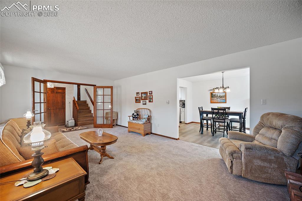 Spacious living room with French doors and brick fireplace opens to the formal dining room.